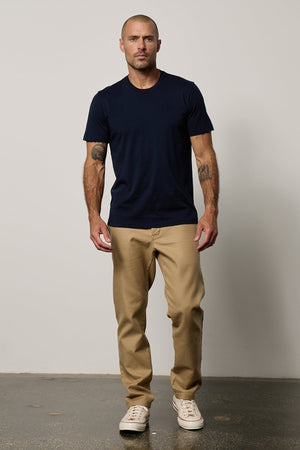 a man wearing a RANDY CREW NECK TEE by Velvet by Graham & Spencer and tan pants.