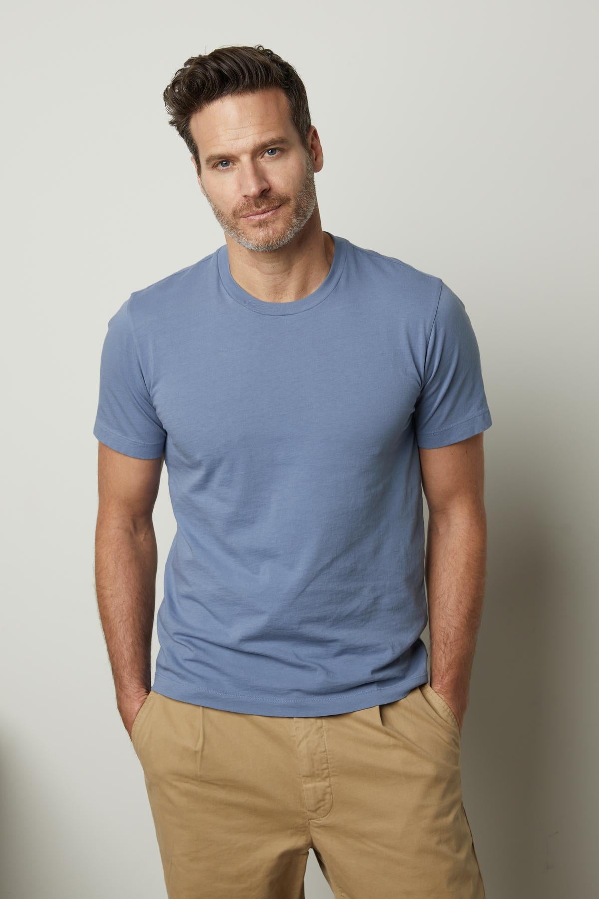   A man wearing a RANDY CREW NECK TEE by Velvet by Graham & Spencer and khaki pants. 
