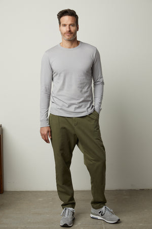 A man wearing a Velvet by Graham & Spencer grey long-sleeved STRAUSS CREW NECK TEE and khaki pants.