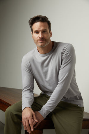 A man wearing a grey Velvet by Graham & Spencer long sleeved shirt and green pants.