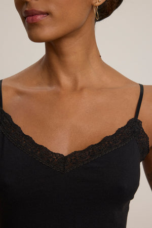 A woman models the Velvet by Graham & Spencer INDIE LACE CAMI, a black tank top with lace trim and thin straps, shown from shoulders to chest against a plain background.