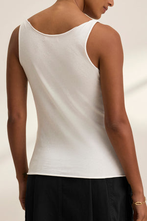 A person is shown from the back against a light background, wearing the Velvet by Graham & Spencer KIM TANK TOP—a white, sleeveless cotton essential with a scoop neckline—paired with black pants.