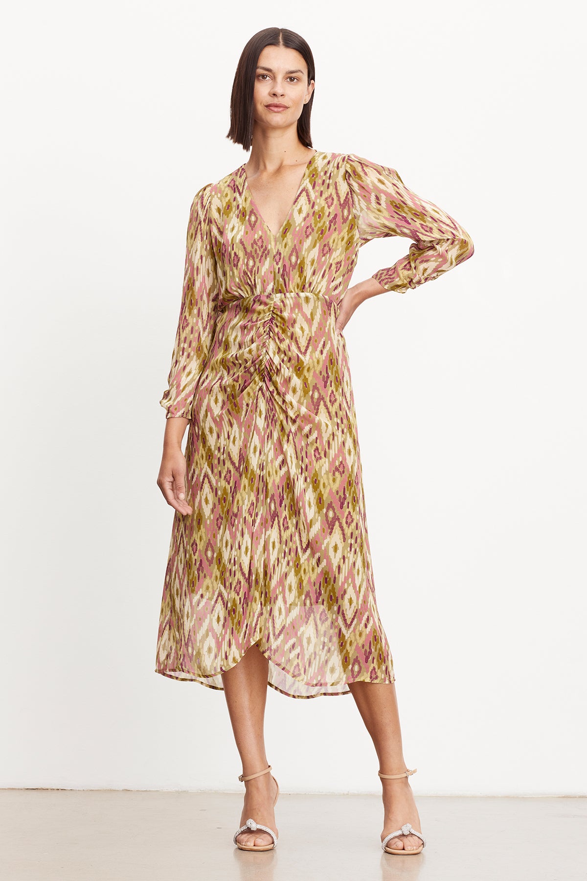 The chic model is wearing a CAILEY PRINTED RUCHED DRESS by Velvet by Graham & Spencer that has a flattering fit and features a v-neckline.-35577738330305