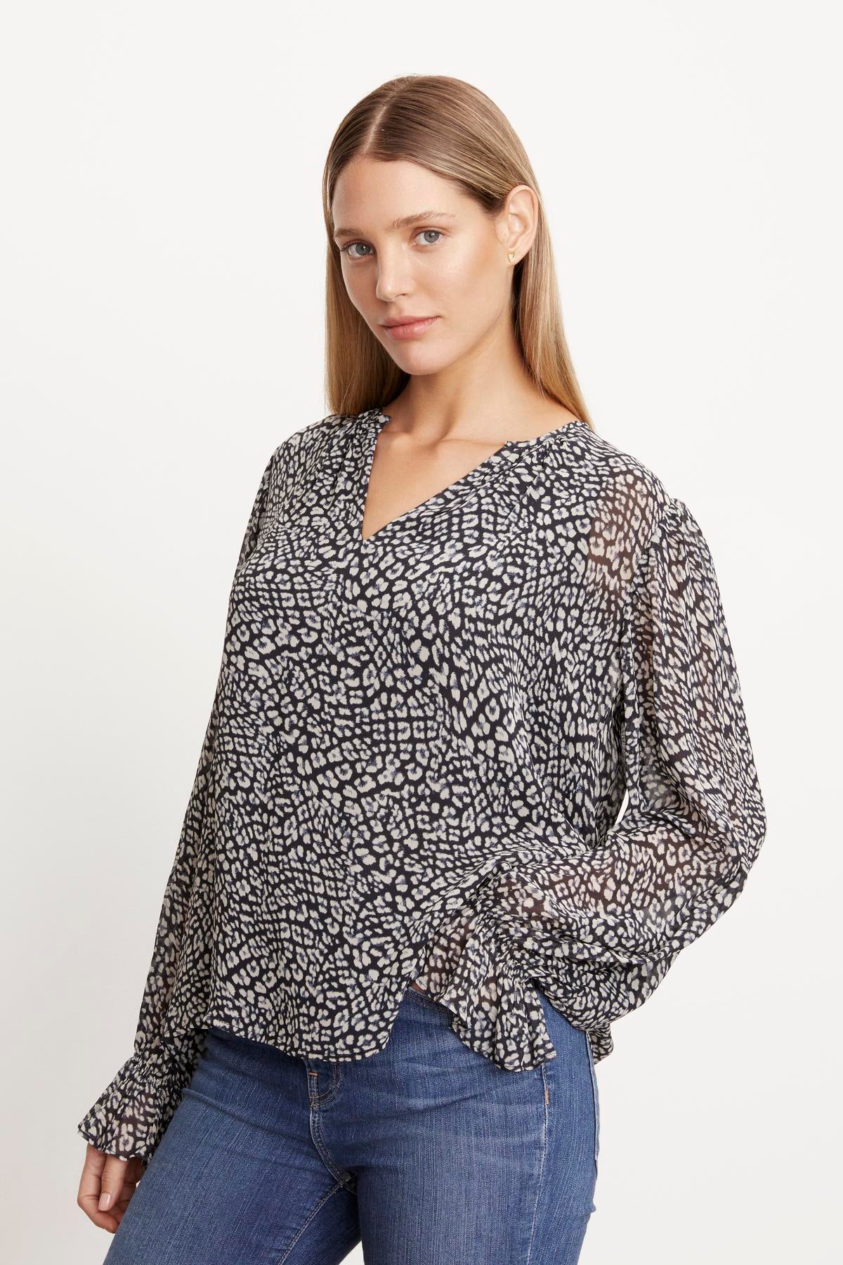 A woman is wearing an elegant Kathy Printed V-Neck Blouse, showcasing femininity in her ensemble with a black and white print by Velvet by Graham & Spencer.-35624038826177