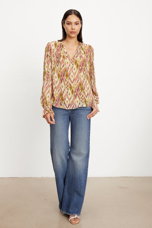 The model is wearing a Velvet by Graham & Spencer Kathy Printed V-Neck Blouse.