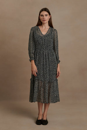 A woman wearing a Leslie Printed Boho Dress by Velvet by Graham & Spencer, which is a flared skirt midi dress with a lightweight viscose georgette overlay.