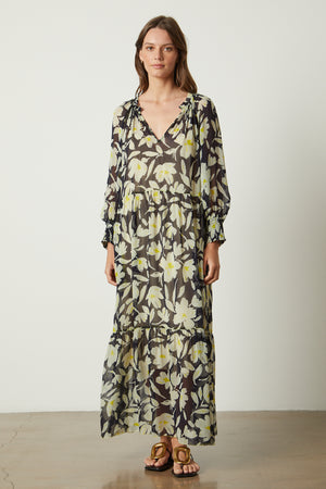 a woman wearing a black and yellow floral Serena printed maxi dress from Velvet by Graham & Spencer.