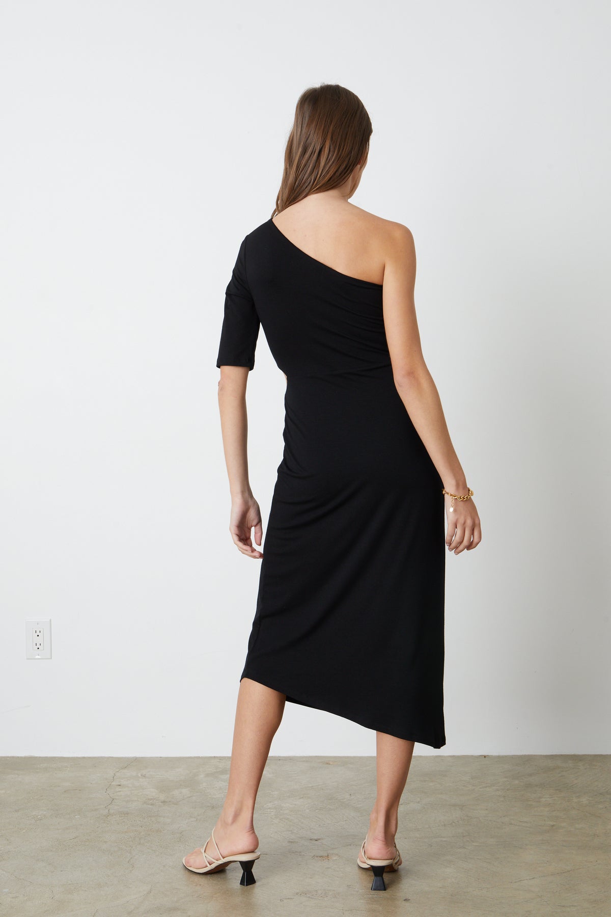   The back view of a woman wearing a CAILIN CUT OUT ONE SHOULDER DRESS by Velvet by Graham & Spencer. 