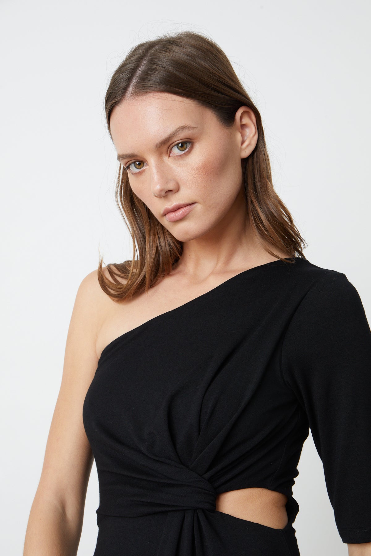The model is wearing a black CAILIN CUT OUT ONE SHOULDER DRESS by Velvet by Graham & Spencer.-26552696570049