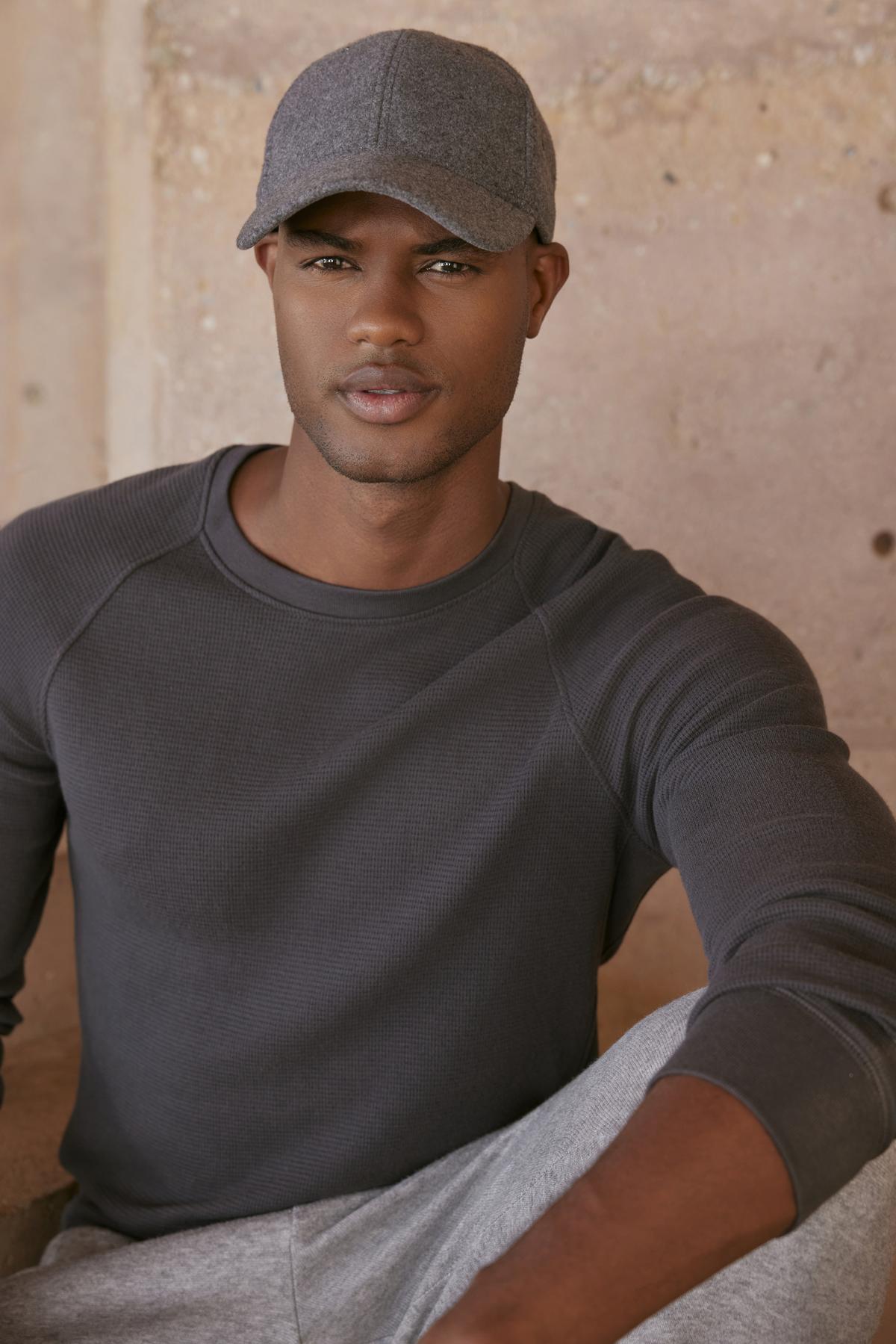   A black man wearing a comfortable fit gray Velvet by Graham & Spencer hat and sweatpants, the GLEN THERMAL CREW. 