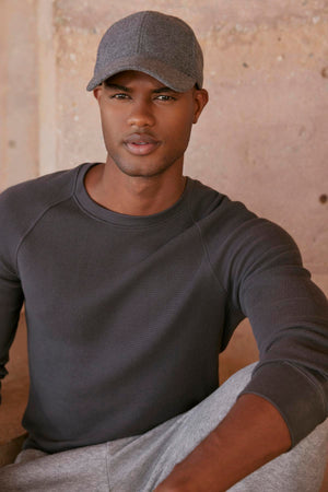 A black man wearing a comfortable fit gray Velvet by Graham & Spencer hat and sweatpants, the GLEN THERMAL CREW.