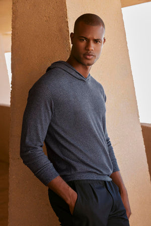 A black man in a Velvet by Graham & Spencer Colin Thermal Hoodie leaning against a wall.