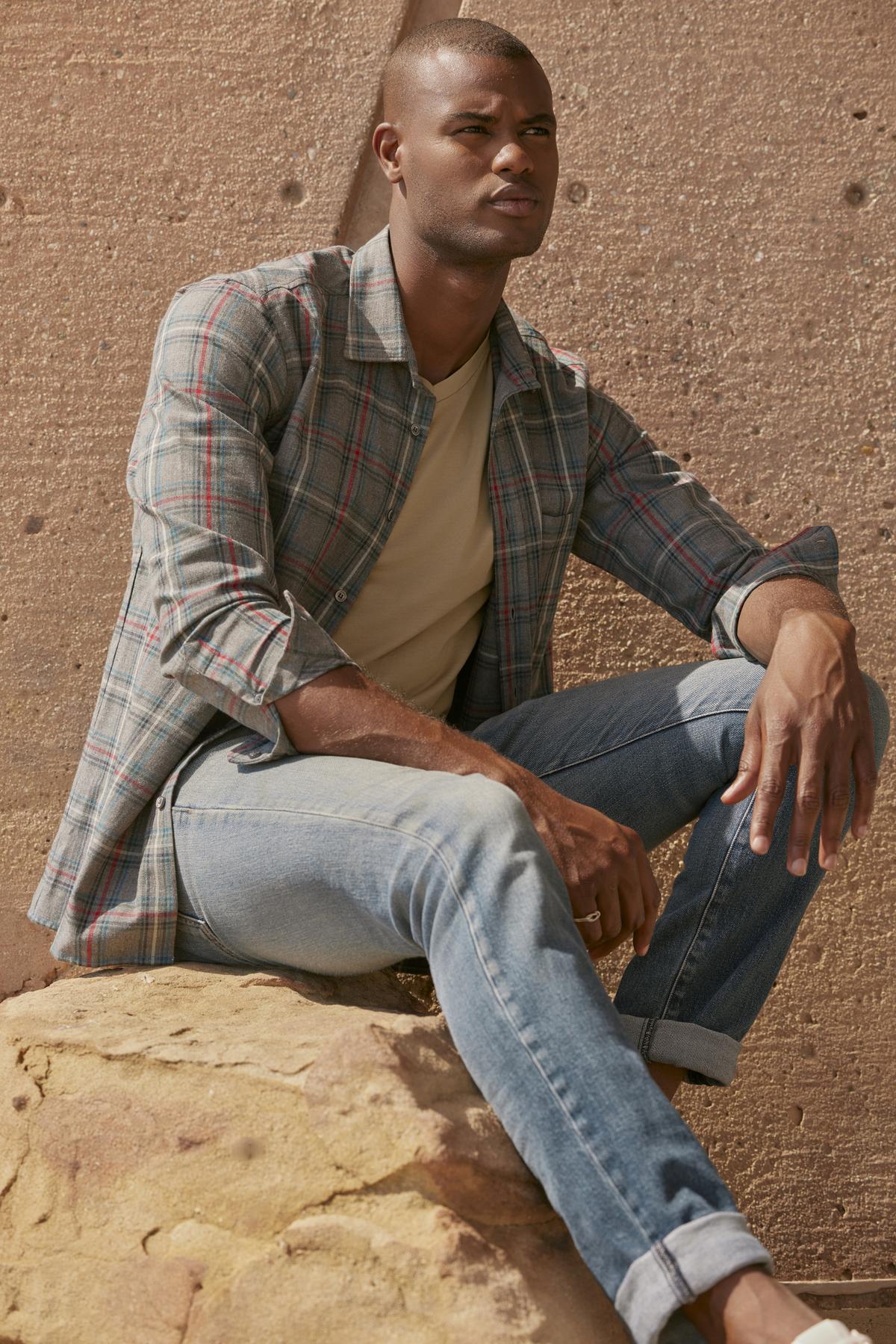 A man sitting on a rock, wearing Velvet by Graham & Spencer's WILDER PLAID BUTTON-UP SHIRT, made with lightweight cotton woven fabric.-35472160850113