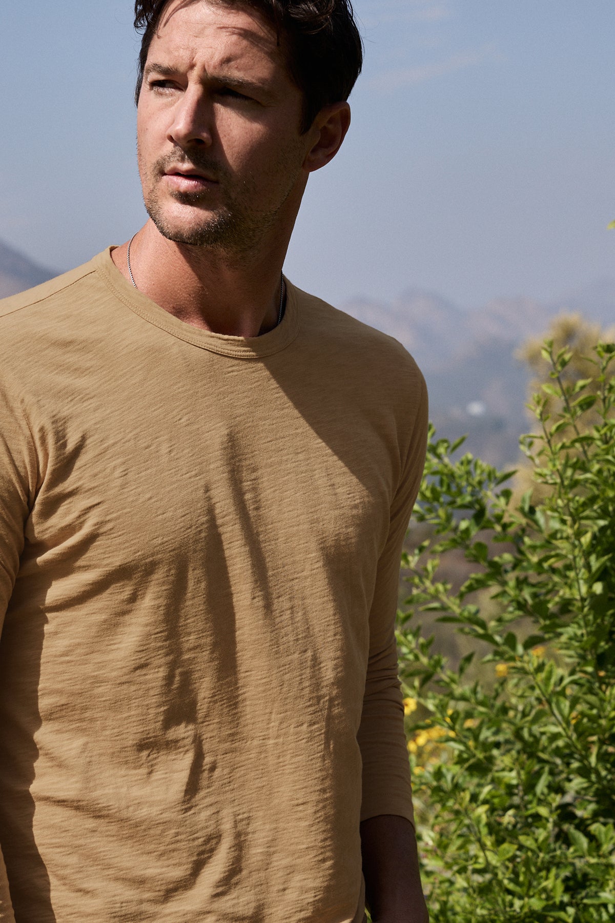 Model standing outdoors wearing Kai Crew Neck Long Sleeve Tee in camel color front detail-26630571294913