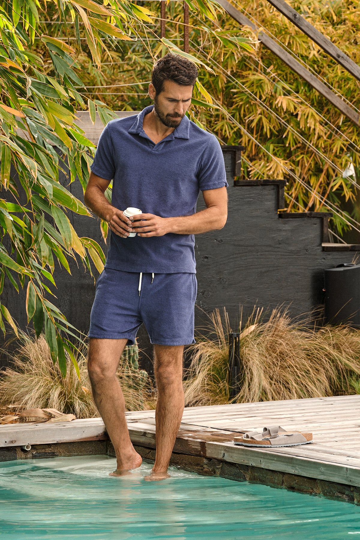   a man in a Velvet by Graham & Spencer BORIS TERRY POLO shirt and shorts standing next to a pool. 