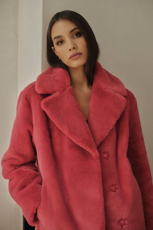 A chic model wearing a cozy pink Velvet by Graham & Spencer RAQUEL FAUX LUX FUR JACKET.
