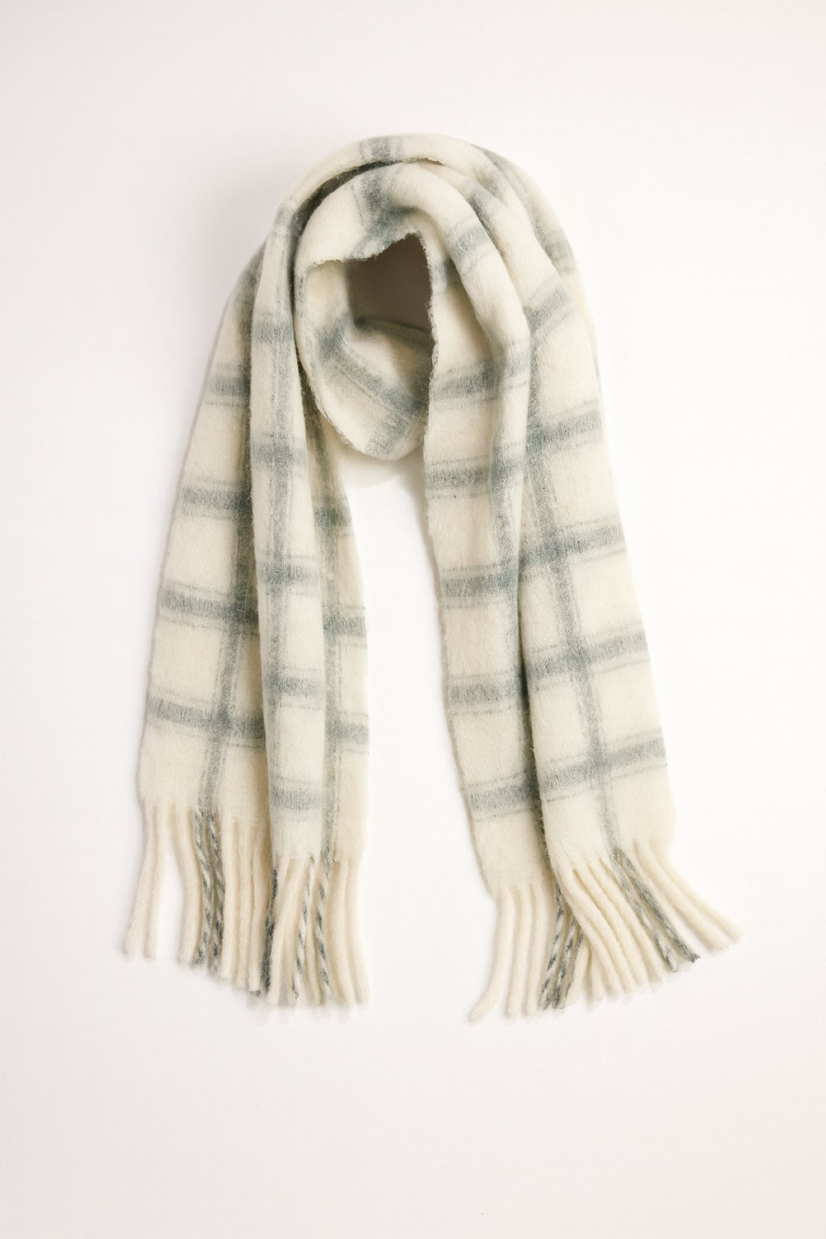 The WARM WINDOW PLAID SCARF by Velvet by Graham & Spencer features a cream base with a gray plaid pattern and fringed ends, displayed flat on a white background.