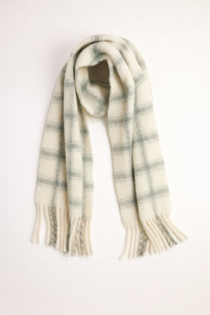 The WARM WINDOW PLAID SCARF by Velvet by Graham & Spencer features a cream base with a gray plaid pattern and fringed ends, displayed flat on a white background.