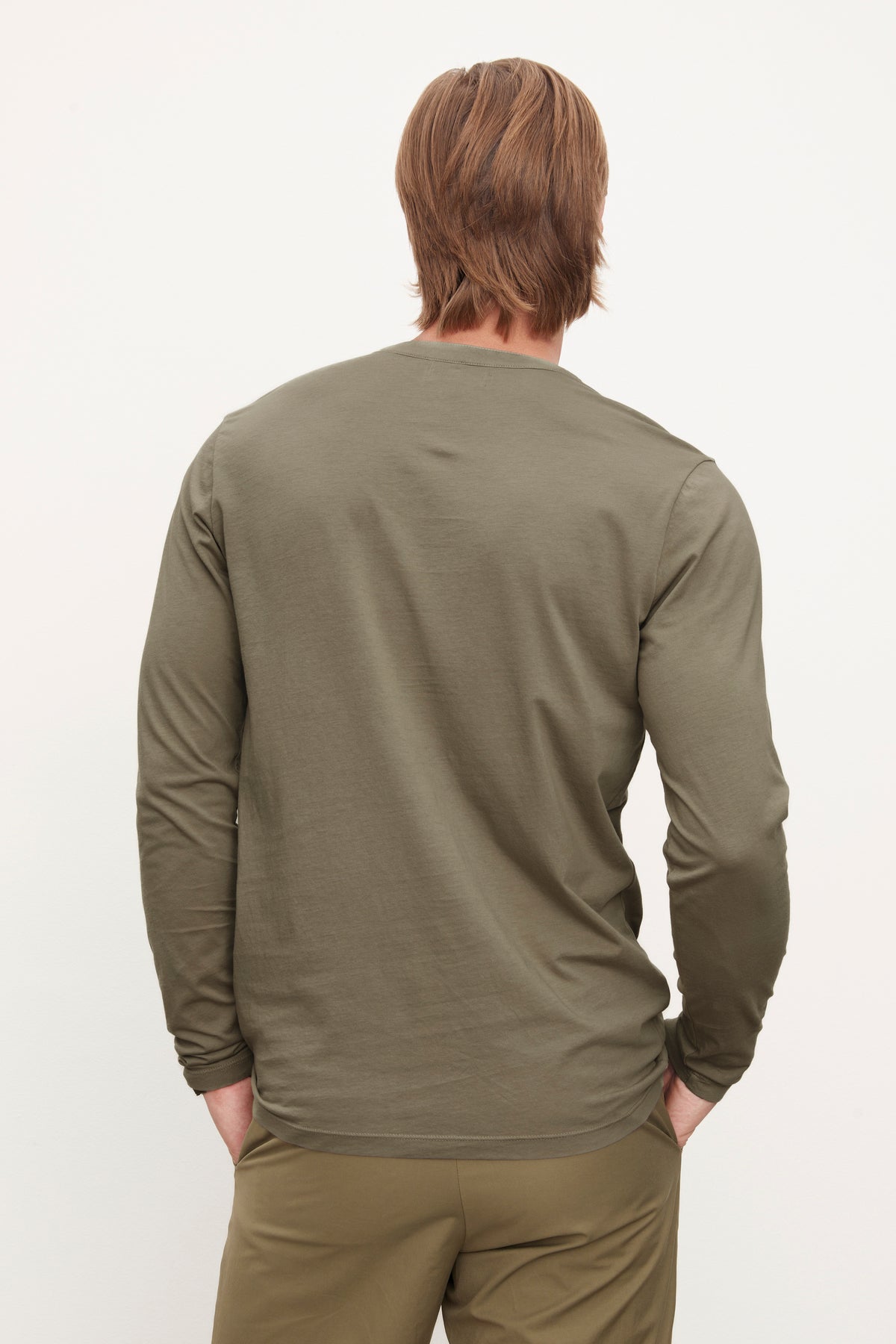   Man in olive green Velvet by Graham & Spencer ALVARO COTTON JERSEY HENLEY shirt and trousers, viewed from the back, standing against a white background. 