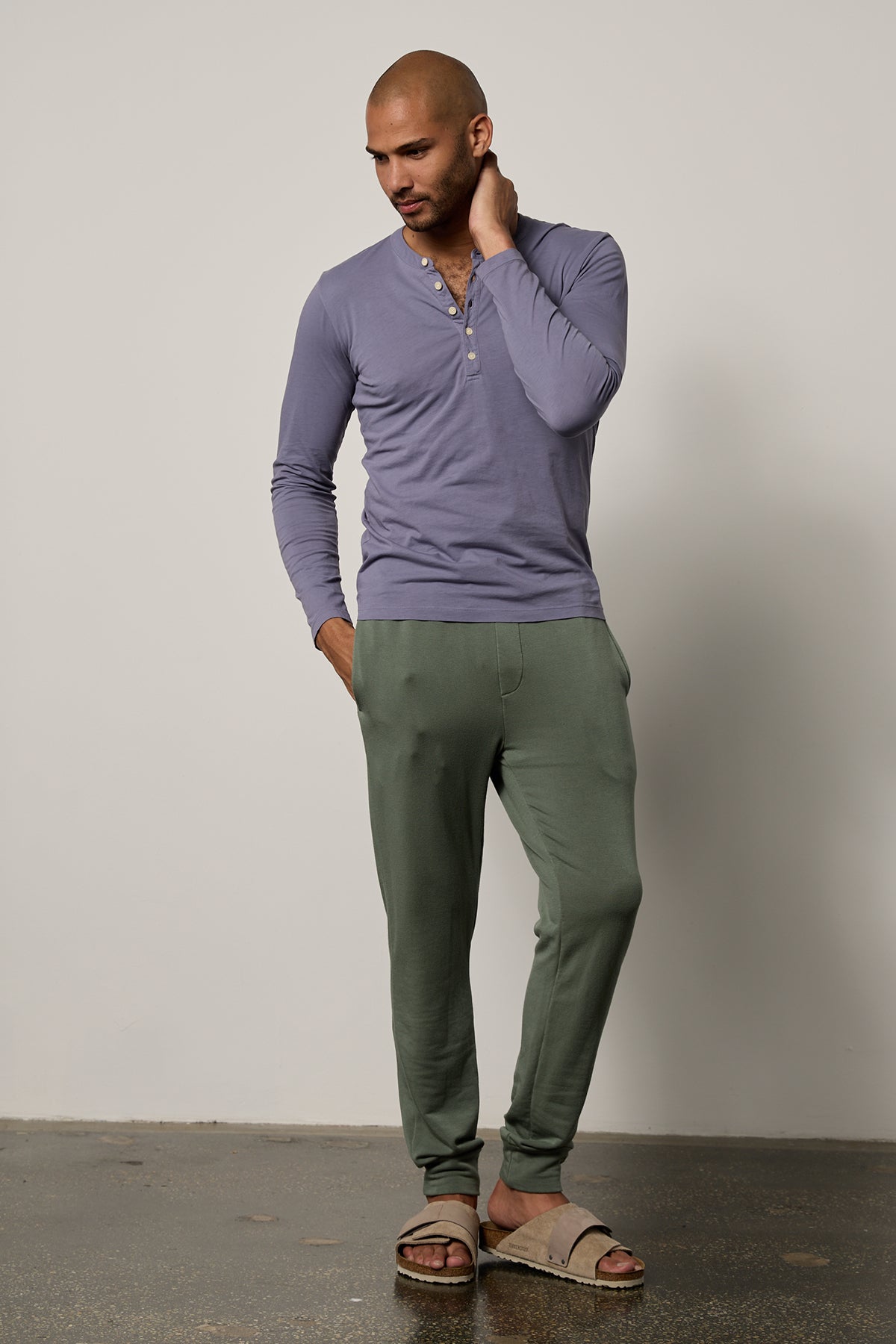   A man in a purple t-shirt and green Velvet by Graham & Spencer sweatpants for workouts, wearing the Crosby Luxe Fleece Jogger. 