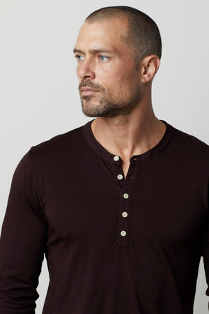 A man wearing a Velvet by Graham & Spencer ALVARO COTTON JERSEY HENLEY shirt with a vintage-look in maroon.