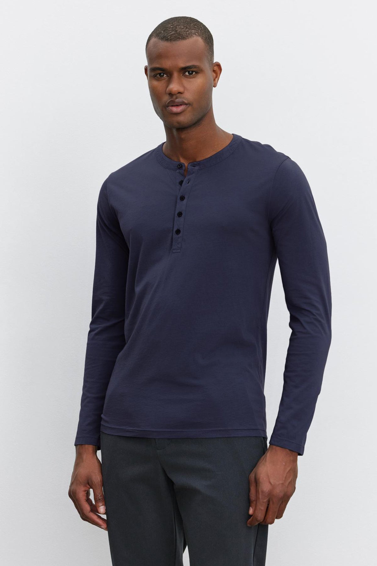   The model is wearing a lightweight navy long sleeve ALVARO COTTON JERSEY HENLEY t-shirt by Velvet by Graham & Spencer. 