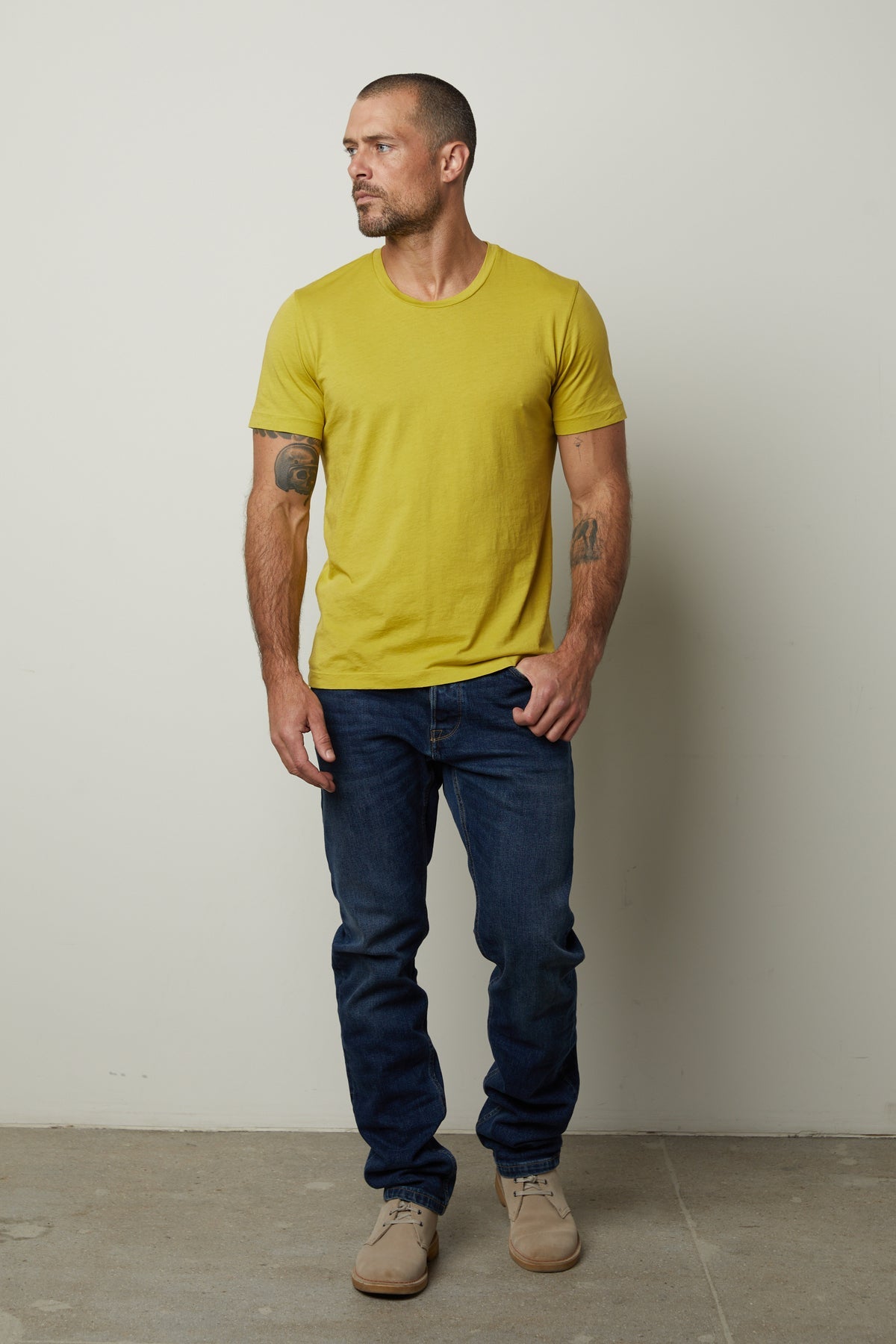 A man wearing a yellow Velvet by Graham & Spencer Howard Whisper Classic Crew Neck Tee and jeans.-35782849069249