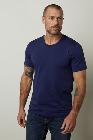 A man wearing a Velvet by Graham & Spencer HOWARD WHISPER CLASSIC CREW NECK TEE in a flawless fit and jeans.