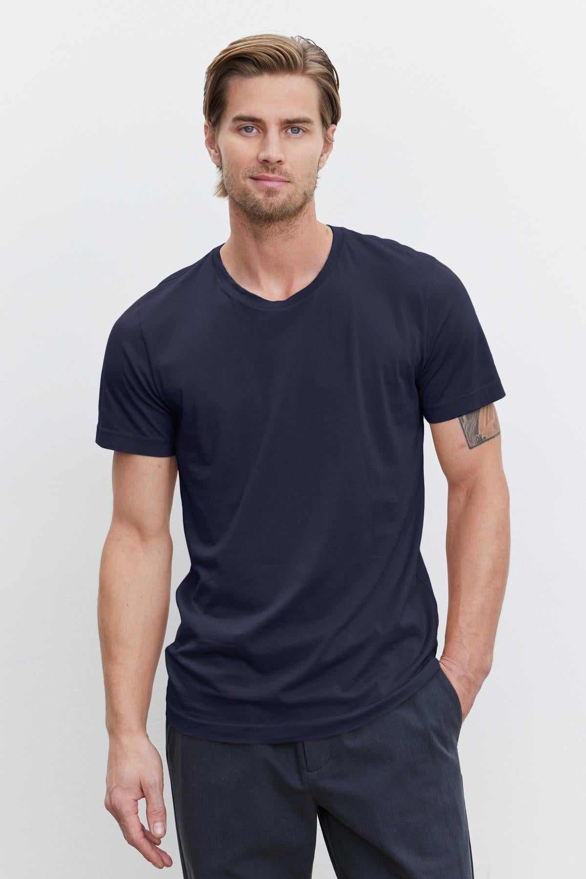   A man wearing a navy v-neck t-shirt made of lightweight cotton knit with a vintage-feel softness, the HOWARD WHISPER CLASSIC CREW NECK TEE by Velvet by Graham & Spencer. 
