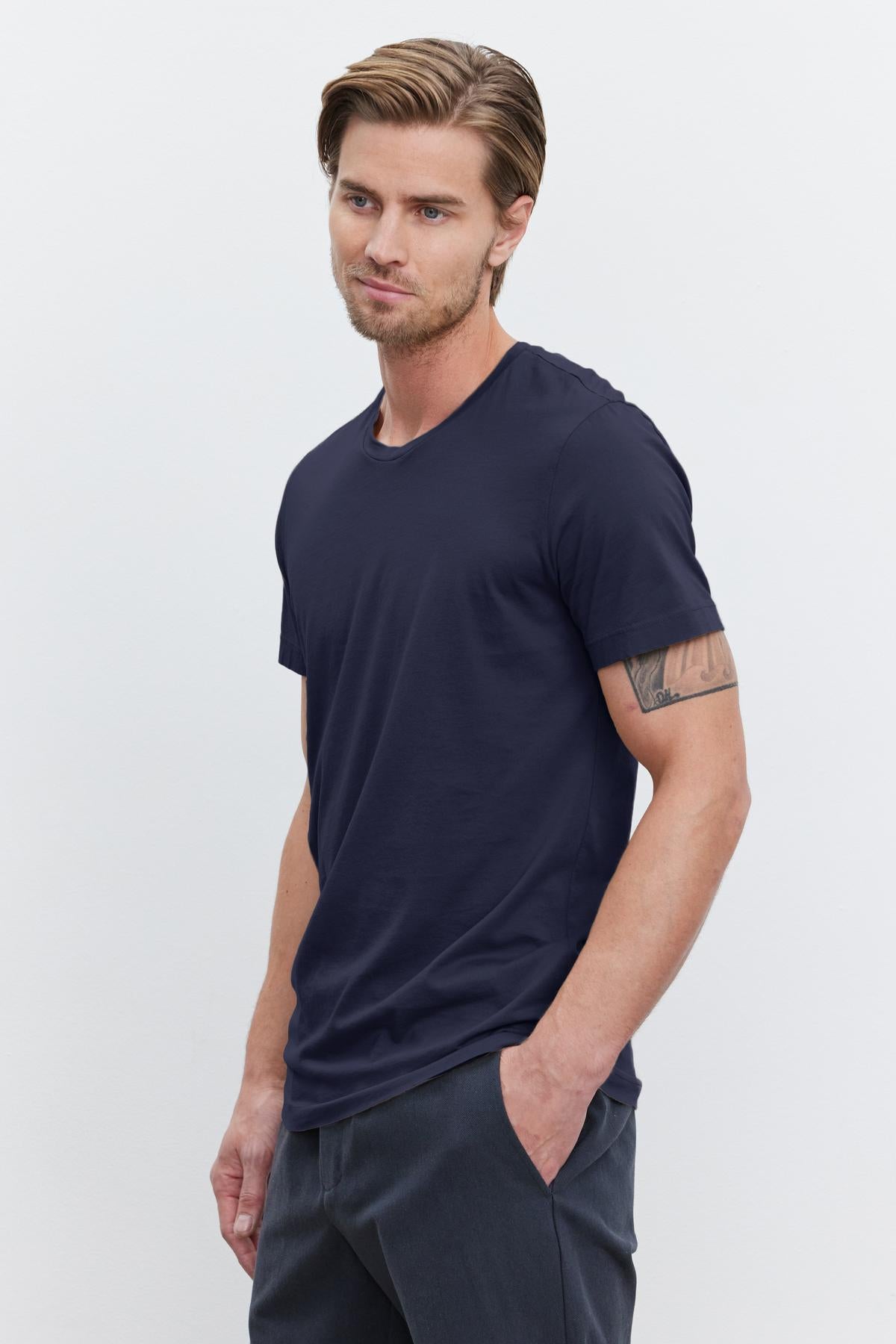   A man wearing a navy HOWARD WHISPER CLASSIC CREW NECK TEE crafted from a lightweight cotton knit fabric by Velvet by Graham & Spencer. 