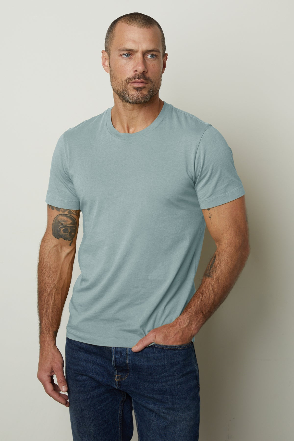 A man wearing the Velvet by Graham & Spencer HOWARD WHISPER CLASSIC CREW NECK TEE, made of lightweight cotton knit for a vintage-feel softness, paired with jeans.-35782849134785