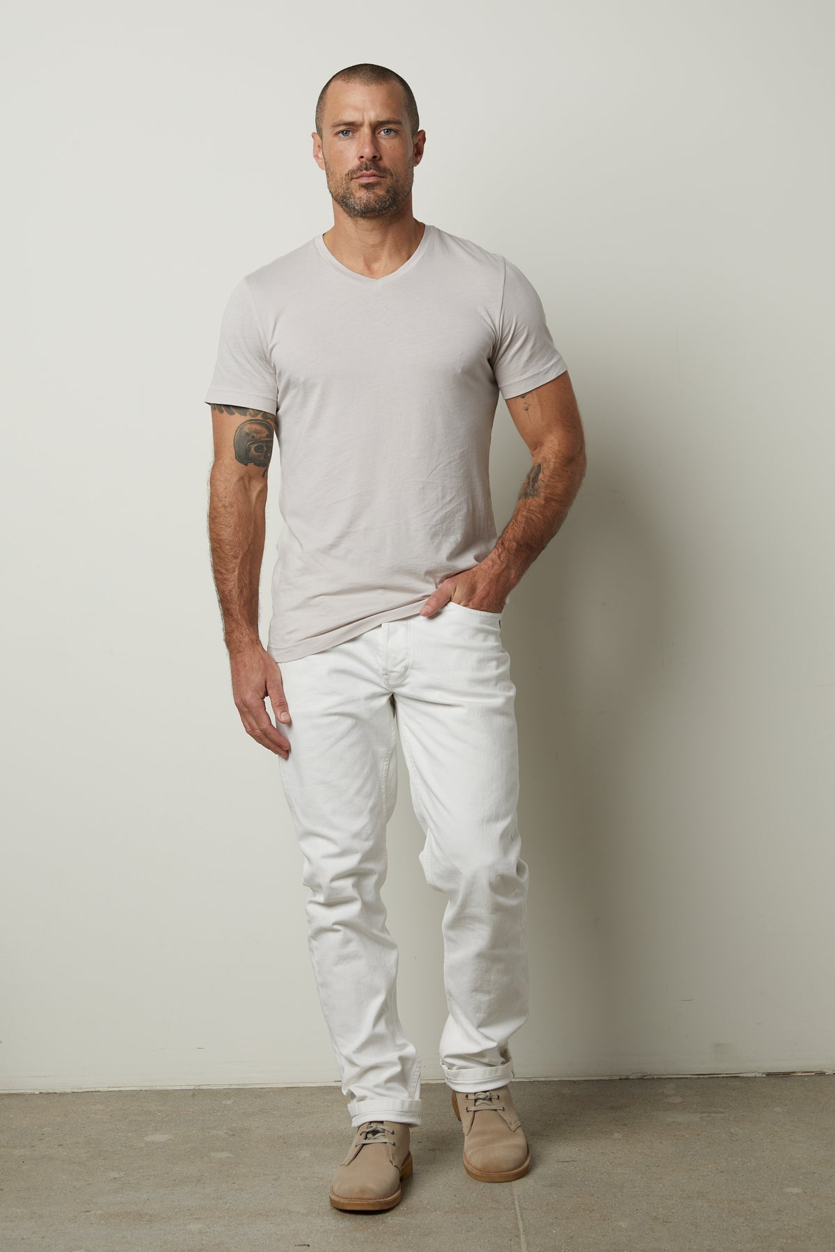 A man wearing white jeans and a Velvet by Graham & Spencer SAMSEN WHISPER CLASSIC V-NECK TEE.-35783134478529