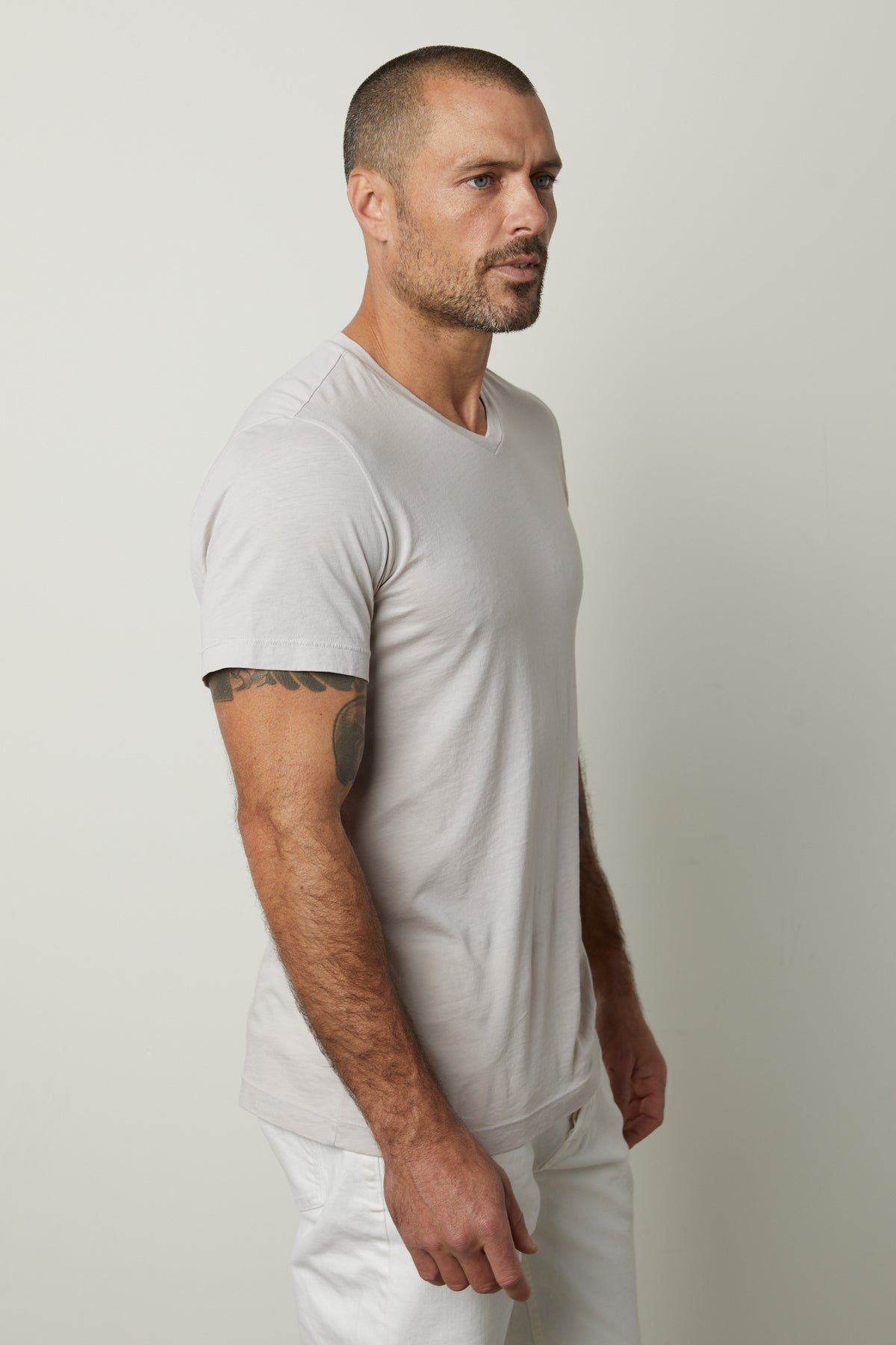 A man wearing white pants and a SAMSEN WHISPER CLASSIC V-NECK TEE by Velvet by Graham & Spencer.-35783134380225