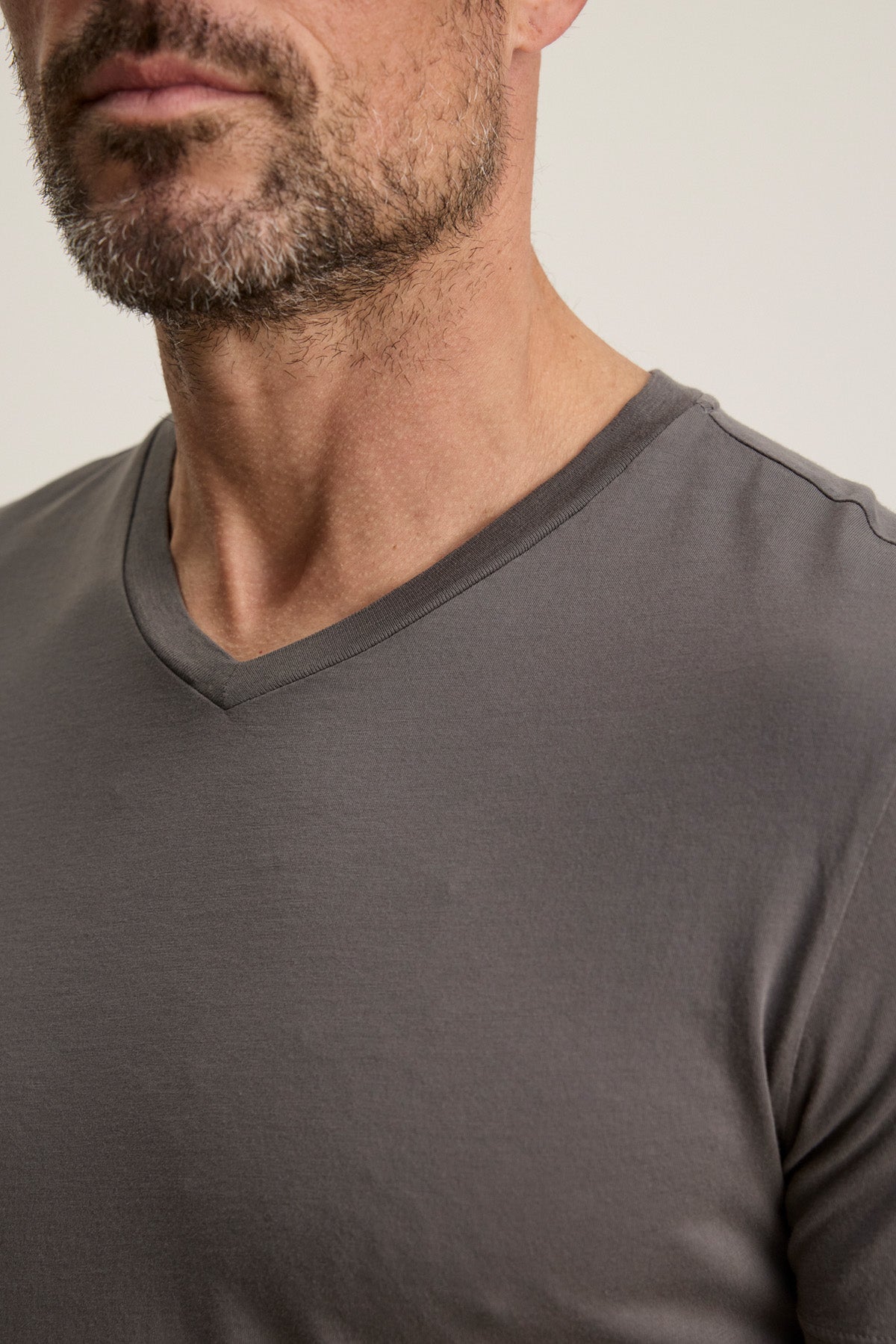 Close-up of a man in the SAMSEN TEE by Velvet by Graham & Spencer—a grey V-neck tee highlighting his lower face, neck, and upper chest with a short beard; ideal for effortless layering.-40452491477185
