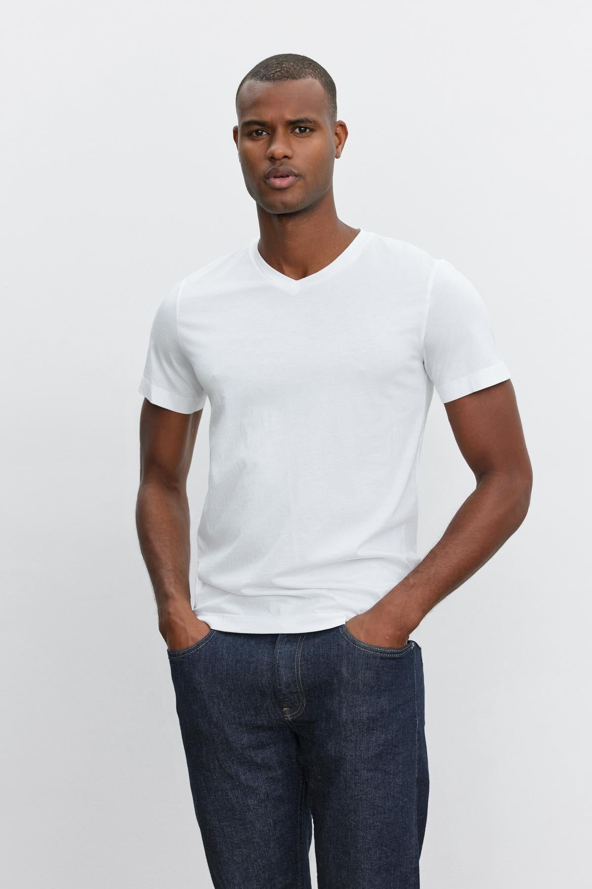 A man wearing a Velvet by Graham & Spencer SAMSEN WHISPER CLASSIC V-NECK TEE and jeans with a whisper knit fabric.-35867445985473