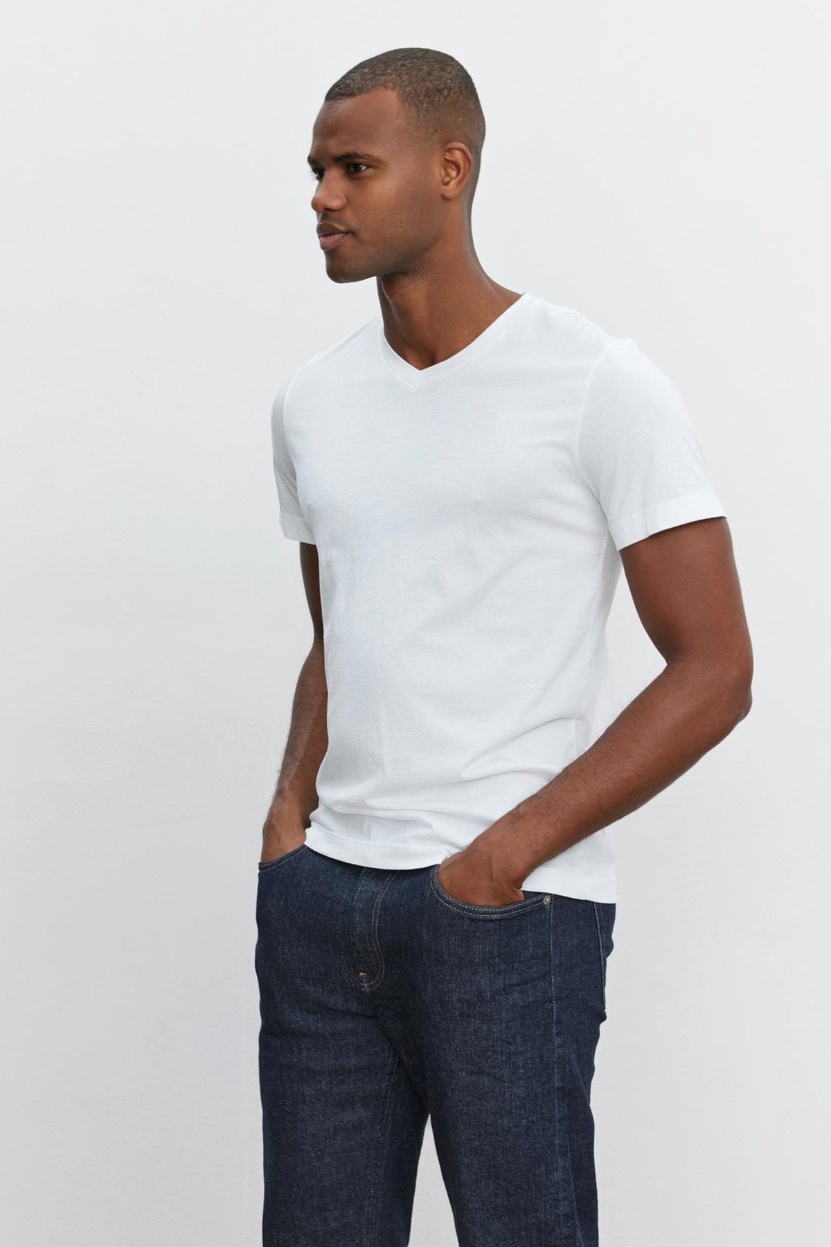   A man wearing a Velvet by Graham & Spencer SAMSEN WHISPER CLASSIC V-NECK TEE and jeans with a utility silhouette. 