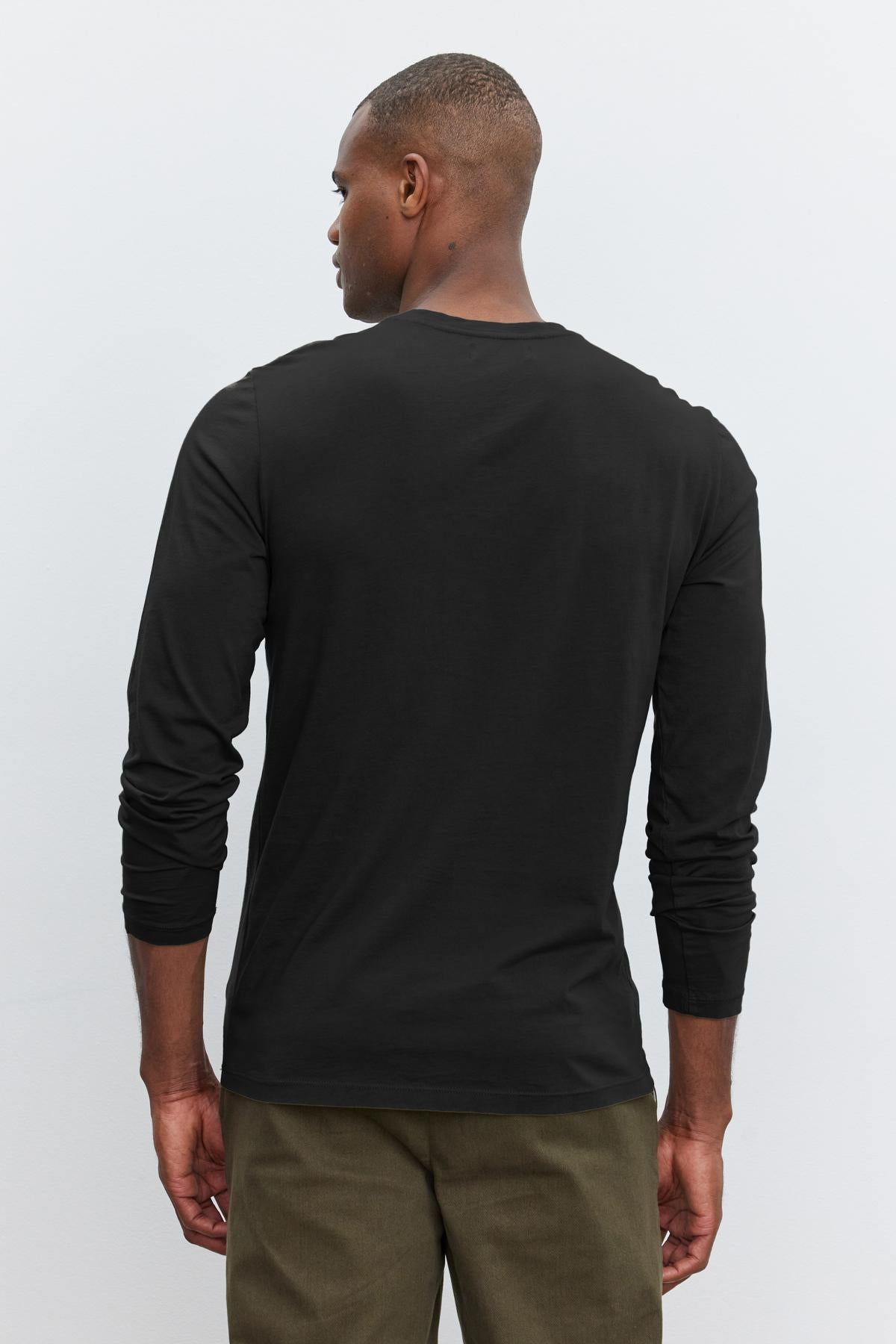 A man viewed from behind wearing a Velvet by Graham & Spencer SKEETER WHISPER CLASSIC CREW NECK TEE and olive green pants, standing against a white background.-36342439280833