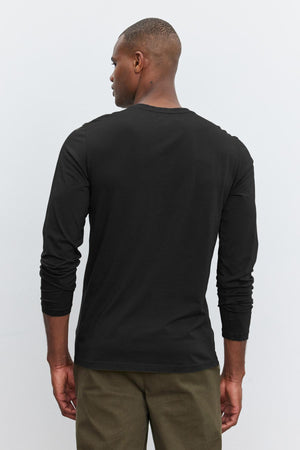 A man viewed from behind wearing a Velvet by Graham & Spencer SKEETER WHISPER CLASSIC CREW NECK TEE and olive green pants, standing against a white background.