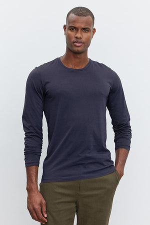 A man in a SKEETER WHISPER CLASSIC CREW NECK TEE by Velvet by Graham & Spencer and olive green pants standing against a white background.