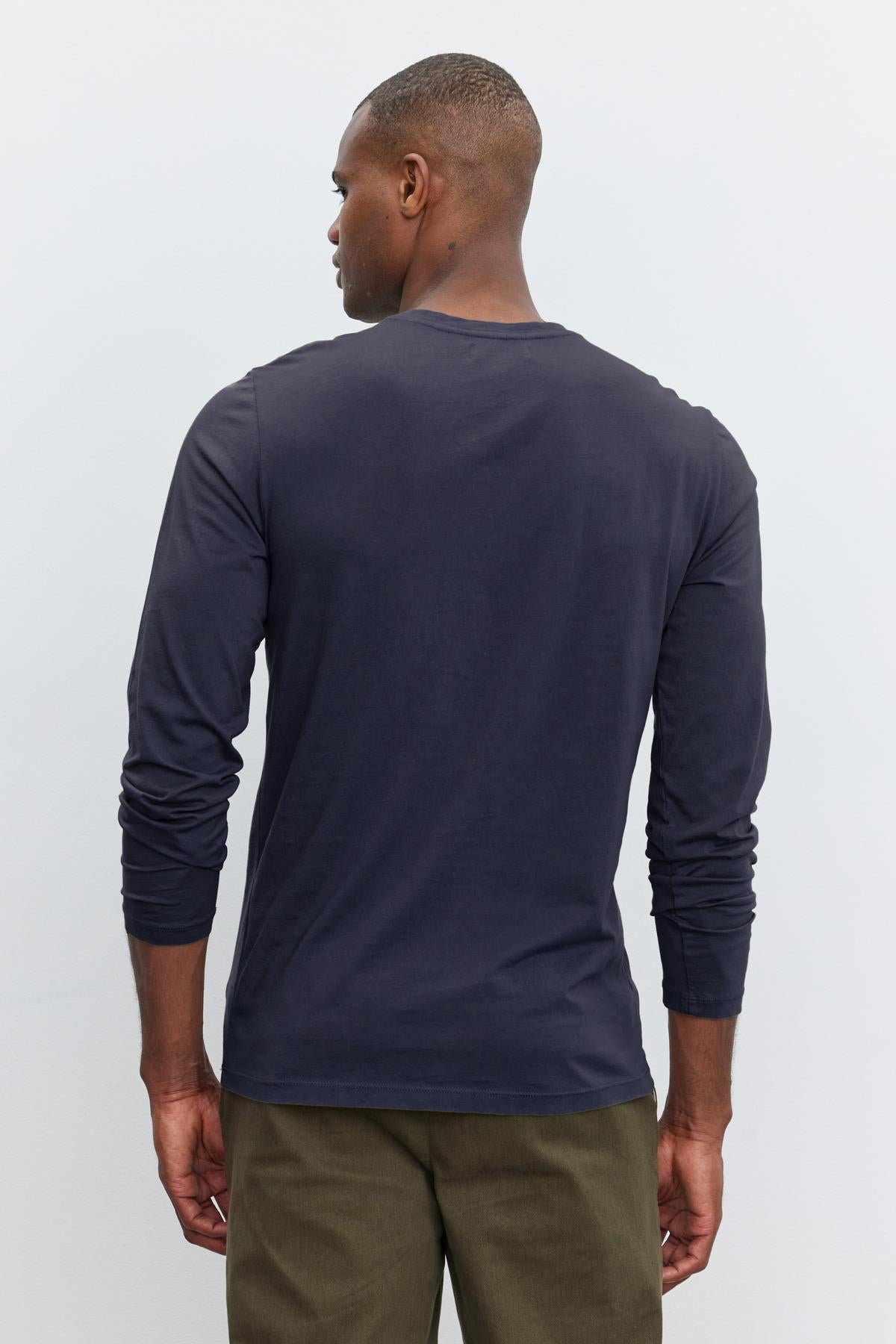 Rear view of a man wearing a Velvet by Graham & Spencer SKEETER WHISPER CLASSIC CREW NECK TEE and olive green garment-dyed pants, standing against a plain white background.-36342439379137