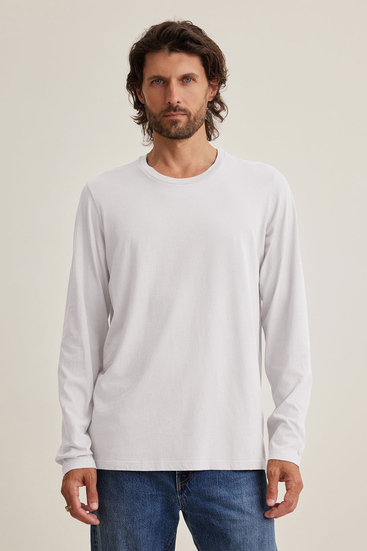 A man in a white SKEETER TEE by Velvet by Graham & Spencer, made from soft Pima jersey, and blue jeans stands facing forward against a neutral background.-39144977072321