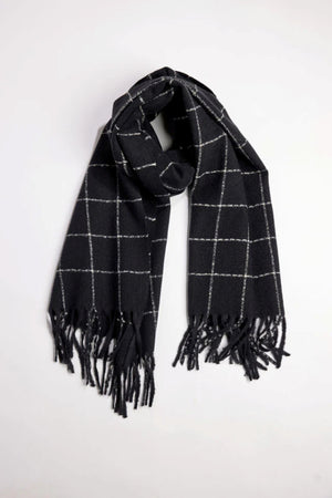 The WINDOWPANE MUFFLER by Velvet by Graham & Spencer is a black scarf featuring a white windowpane check pattern and fringed ends, shown laid flat on a white surface.