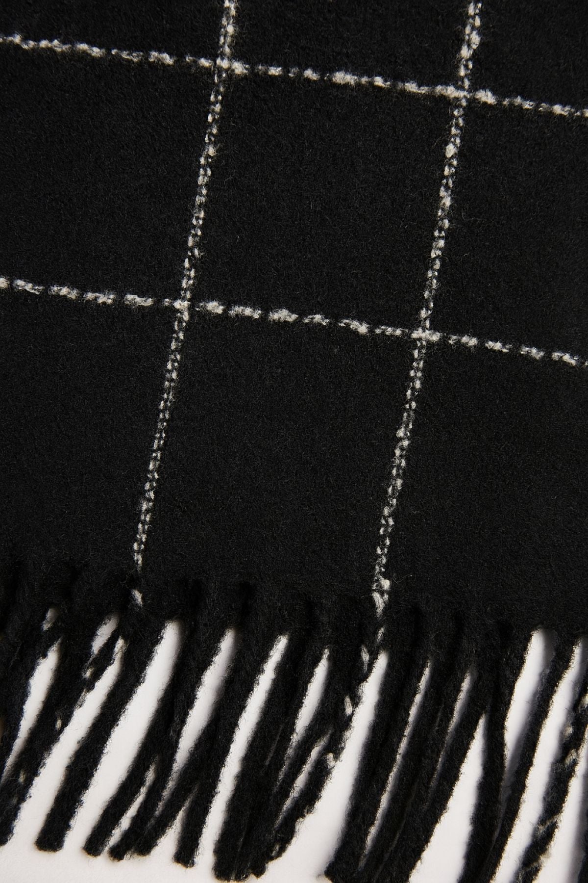 The WINDOWPANE MUFFLER by Velvet by Graham & Spencer features black fabric with white windowpane checks and fringed edges.-40100716347585