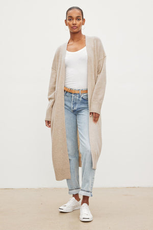 A model wearing jeans and the Velvet by Graham & Spencer LISA WOOL CASHMERE DUSTER CARDIGAN in beige.