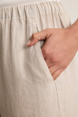 A close-up of a hand in the pocket of the Velvet by Graham & Spencer LOLA LINEN PANT, featuring a lightweight linen fabric and elastic waistband.