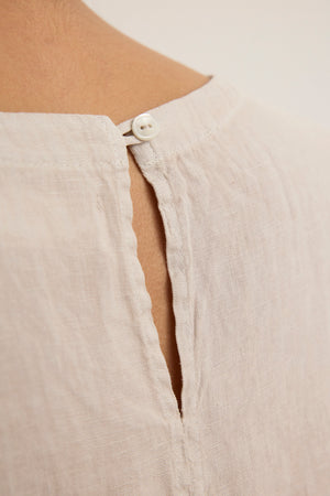 Close-up of the TAVIA LINEN TOP by Velvet by Graham & Spencer, featuring a keyhole opening with a white button at the neckline—a light, airy linen piece ideal for warm days.