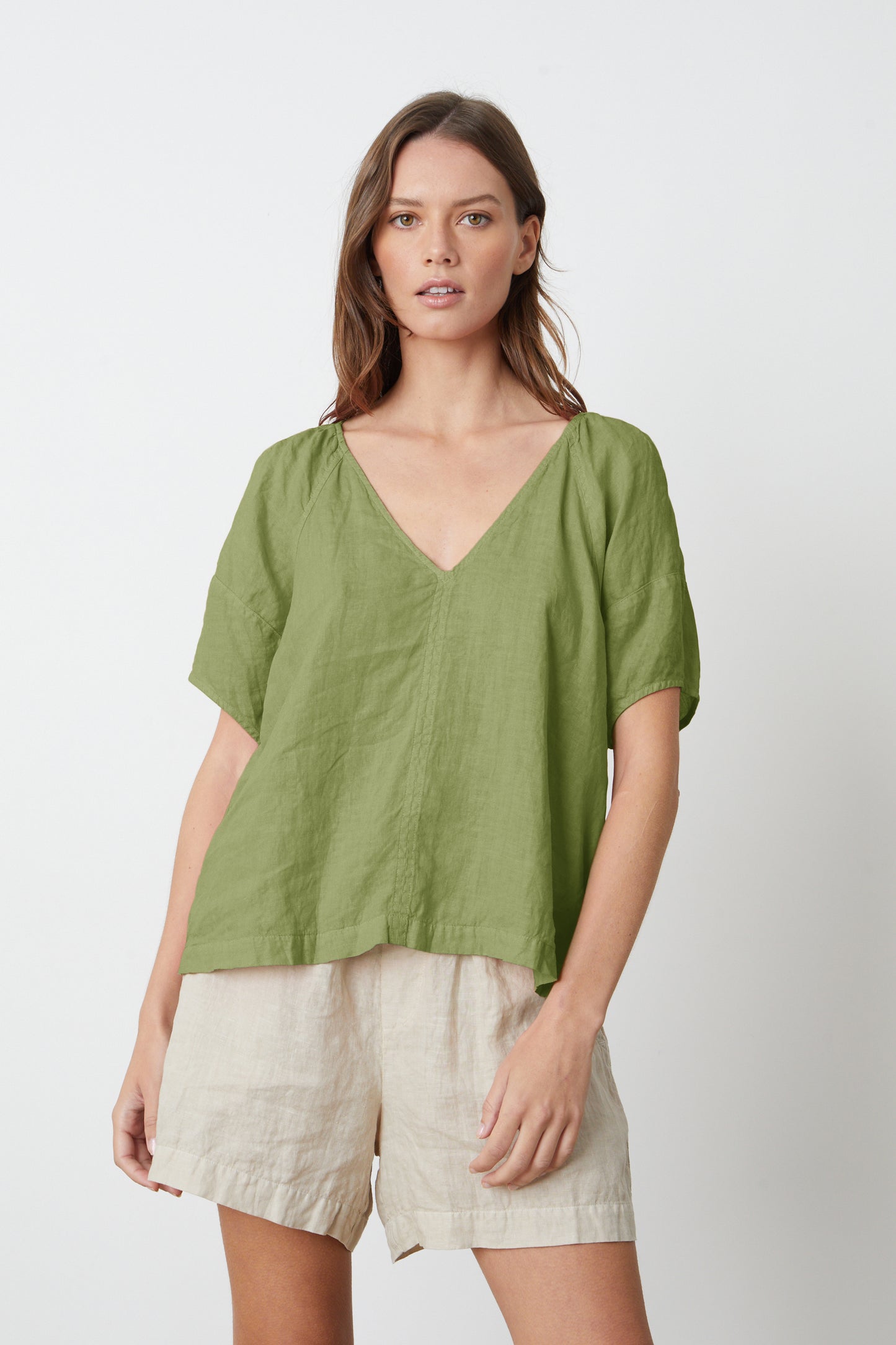 A woman wearing a basil green CALLIN PUFF SLEEVE LINEN TOP by Velvet by Graham & Spencer and Tammy shorts.-26577402233025