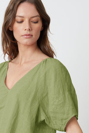 The model is wearing a Velvet by Graham & Spencer CALLIN PUFF SLEEVE LINEN TOP with a V-neck.