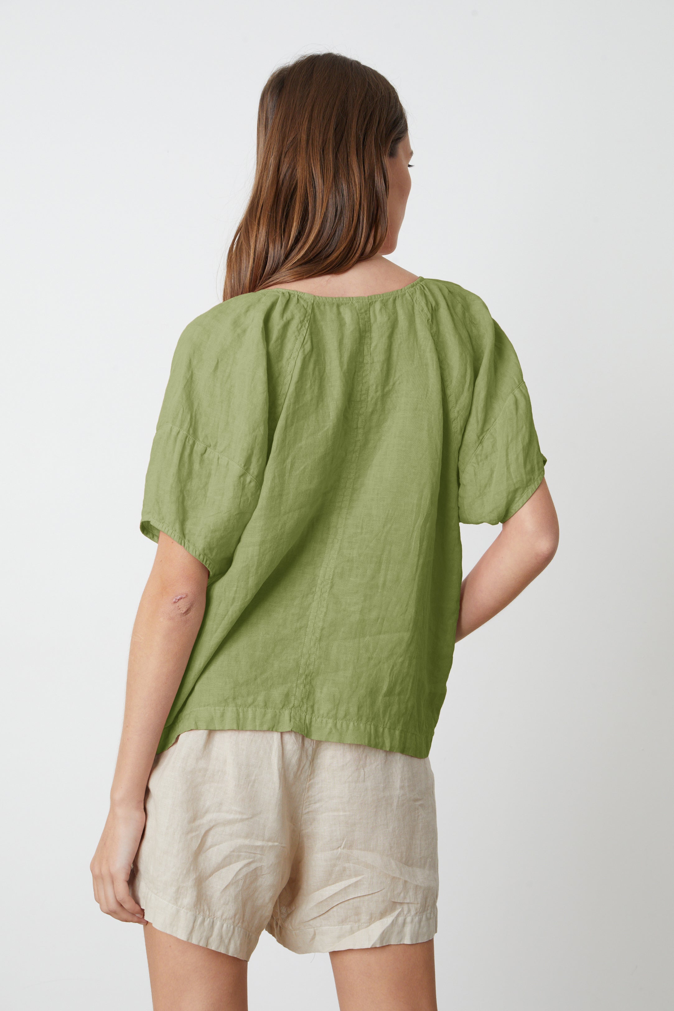   The back view of a woman wearing a Velvet by Graham & Spencer CALLIN PUFF SLEEVE LINEN TOP and Tammy shorts. 