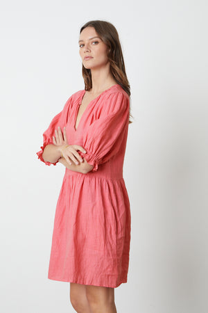 The model is wearing a KAILANI LINEN PUFF SLEEVE DRESS by Velvet by Graham & Spencer with ruffled sleeves.